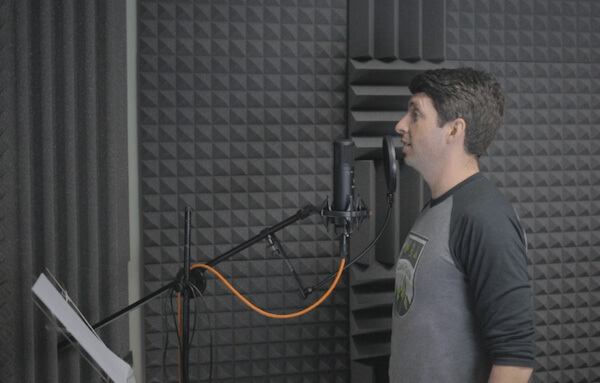 Person speaking into a microphone in an audio recording room